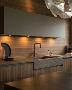 Platsbyggt kök med kombination av köksluckor i trä fanér samt beige laminat, . bänkskiva i dekton kompositsten med integrerad diskho i samma sten.