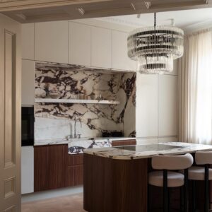 Modern måttandpassat kök i en lägenhet mellan vasasan och östermalm. Köket i en slät kökslucka i ljus greige kulör. Köksö med rundade hörn i träluckor. Bänkskiva och stänkskydd i marmor calacatta viola.