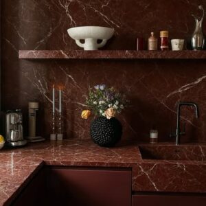 Kök med natursten i rosso och köksskåp i en mörk vinröd kulör.